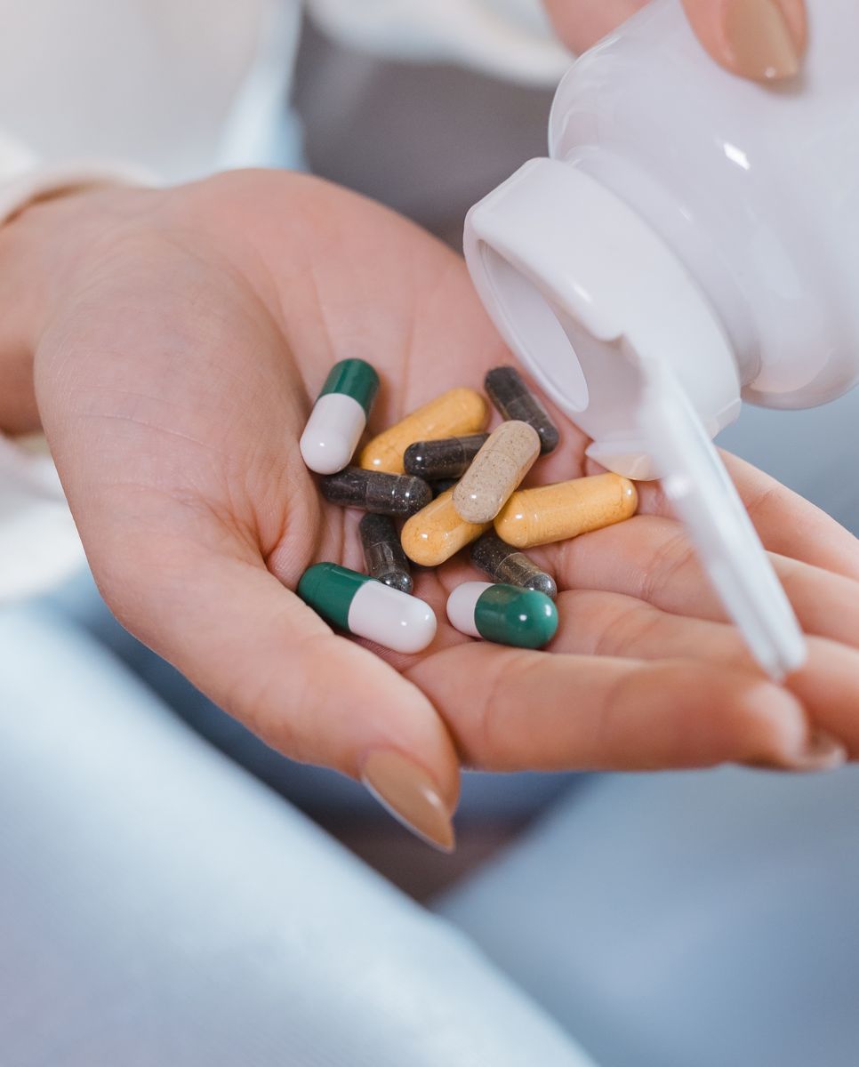 An older hand holding four large tablets