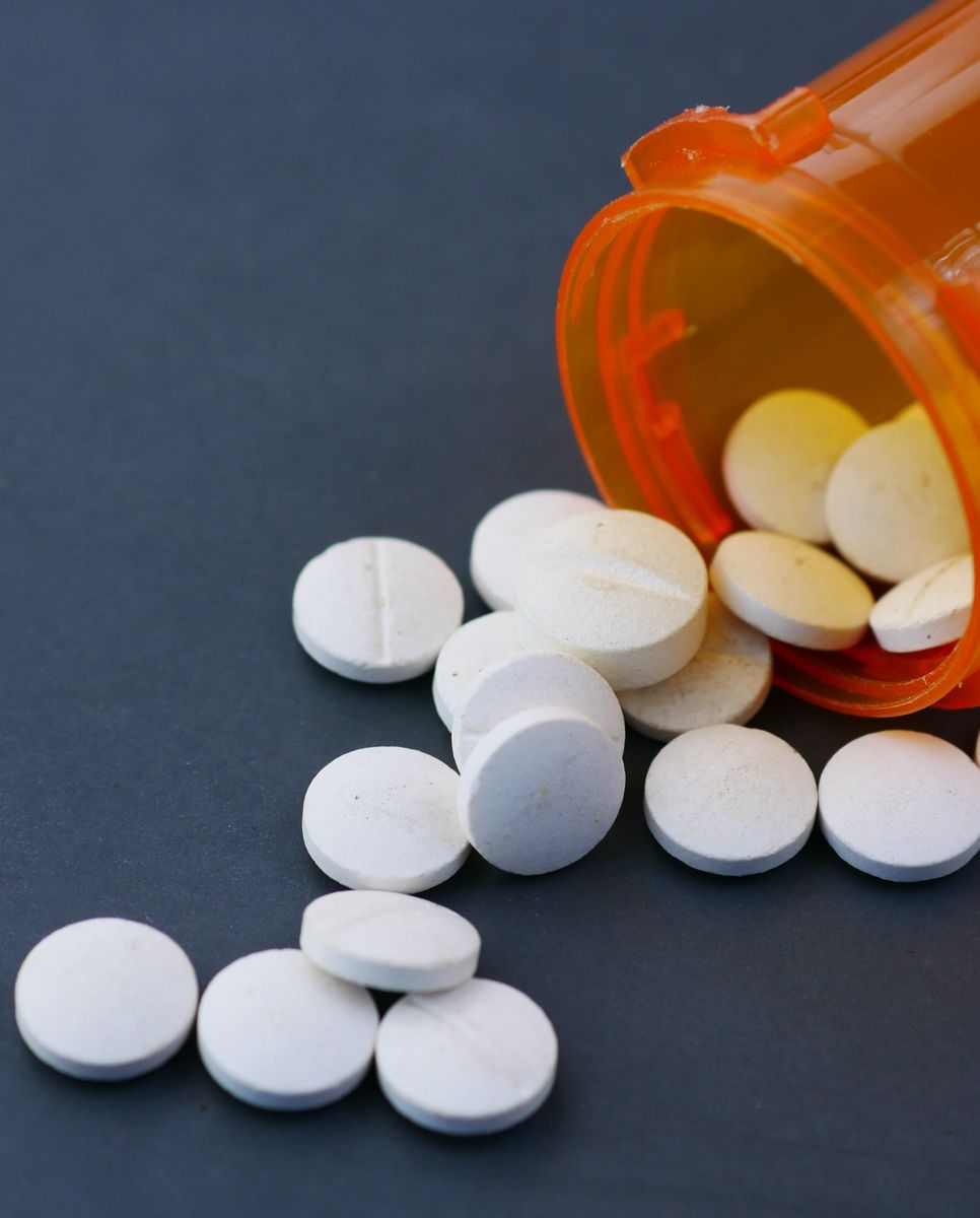 A bottle of large white tablets spilled on a table