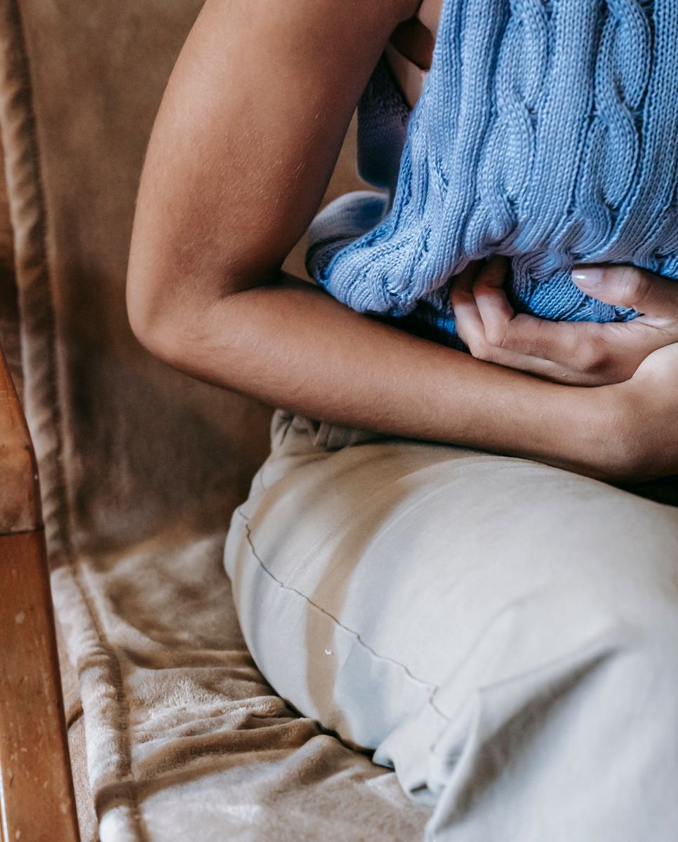 An older woman with a hand on her stomach at a kitchen table